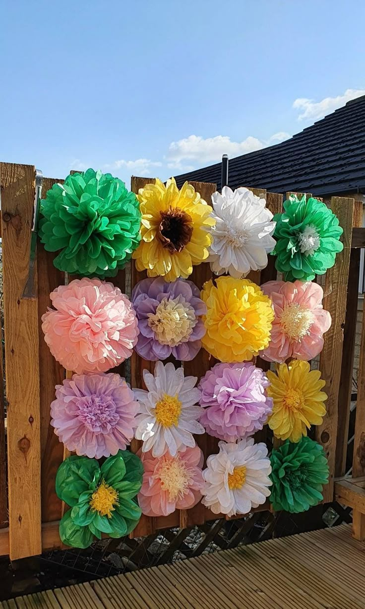 some paper flowers are hanging on a fence