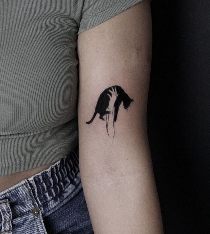 a woman's arm with a small black and white cat tattoo on the left inner arm