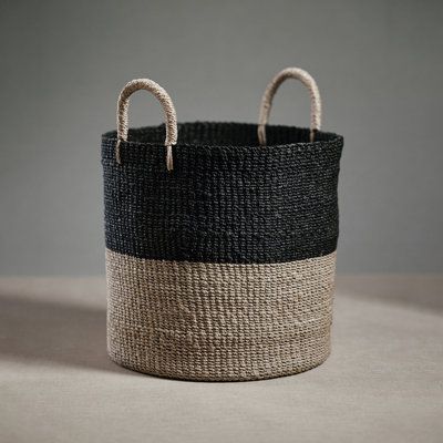 a black and white basket sitting on top of a table next to a gray wall