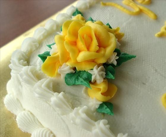 a close up of a cake with frosting and flowers on the icing sheet