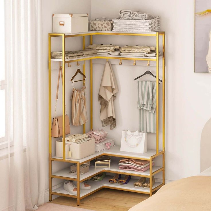 a gold shelf with clothes and bags on it next to a bed in a room