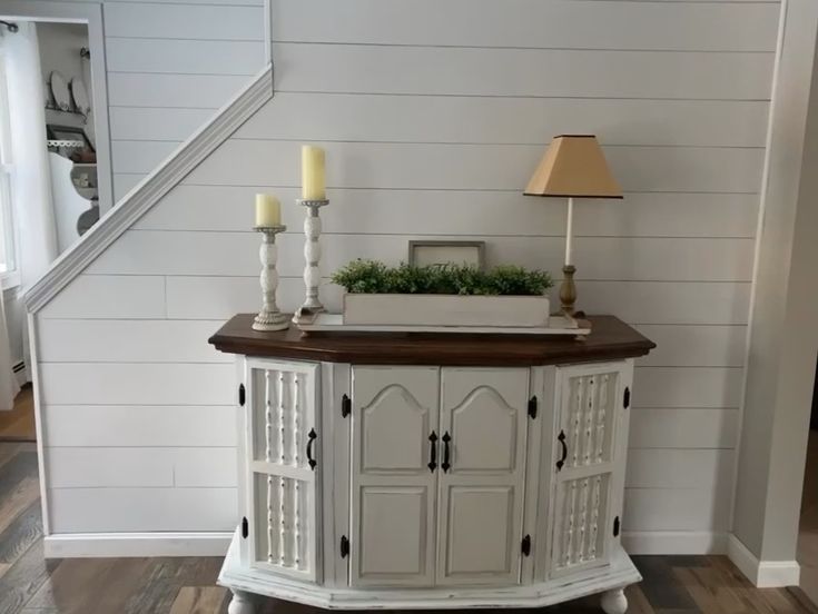 a white cabinet with two candles on top of it