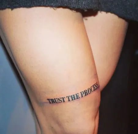 a woman's thigh with the words trust the process tattooed on it