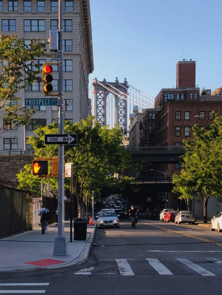 an intersection with traffic lights and cars on the street in front of tall buildings under a bridge