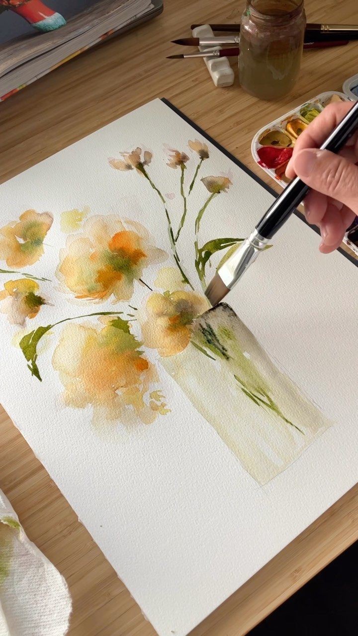 a person is painting flowers with watercolors on paper