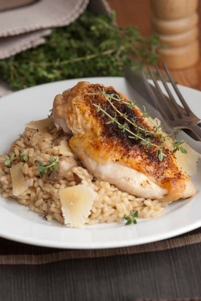 a white plate topped with chicken and rice on top of a wooden table next to a fork