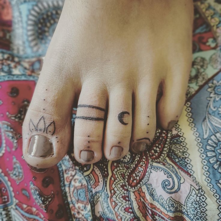 a person's foot with two small tattoos on their toes and one has a crown