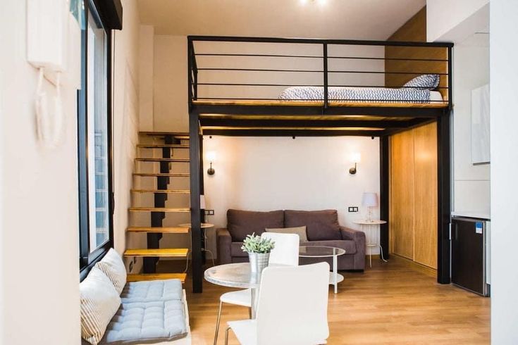 a living room with a loft bed next to a kitchen and dining table in front of it