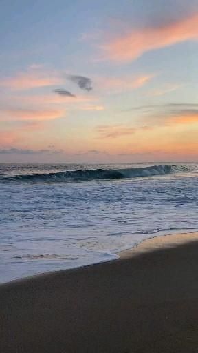 the sun is setting at the beach with waves coming in