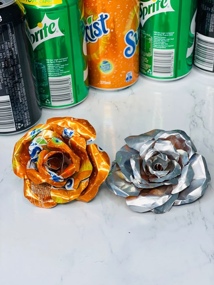 two cans of nest and a flower made out of aluminum foil sitting on a counter