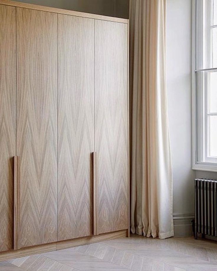 a bedroom with a large wooden closet next to a window and radiator in the corner