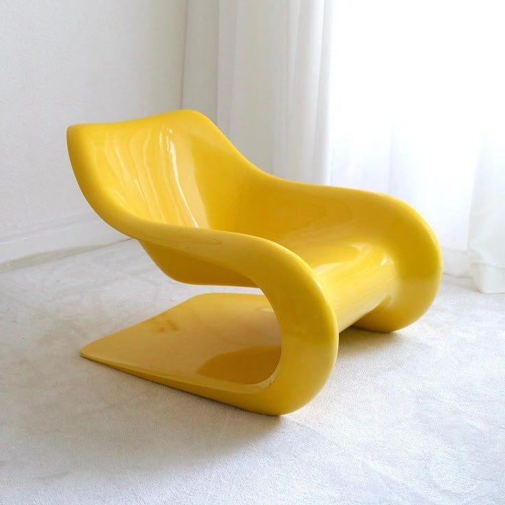 a yellow plastic chair sitting on top of a white floor next to a curtained window