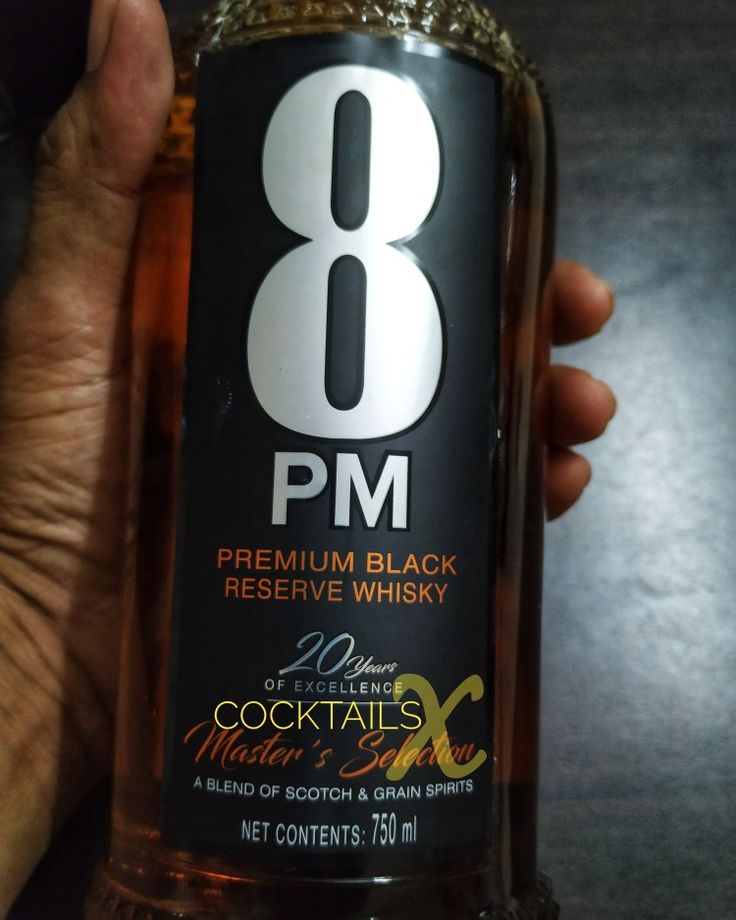 a person holding a bottle of booze with the number eight on it's label