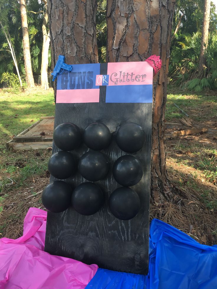 an outdoor sculpture made out of black balls and colored paper on the ground next to a tree