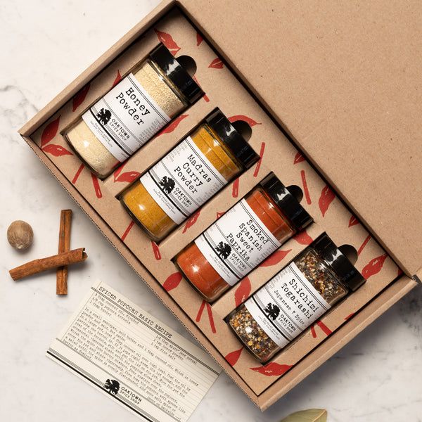 three bottles of spices sit in a box next to cinnamon sticks