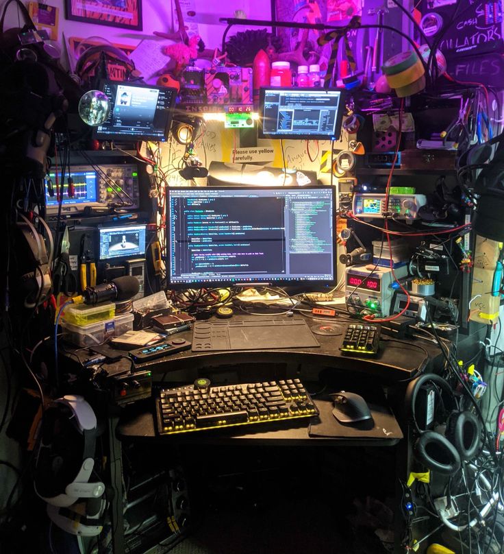 a computer desk with multiple monitors and keyboards on it in a room full of wires