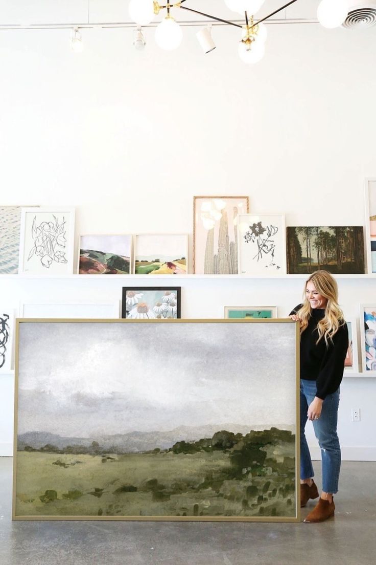 a woman standing next to a large painting