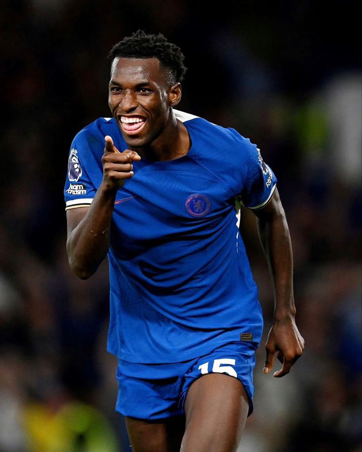 a soccer player is smiling and holding his hand up to his mouth as he runs towards the camera