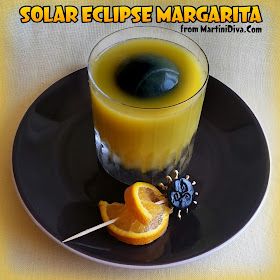 an orange juice in a glass on a black plate