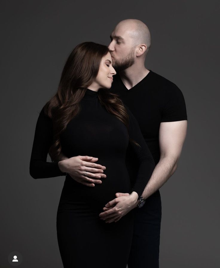 a man and woman standing next to each other with their hands on their stomachs