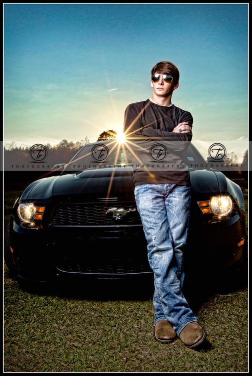 a man standing in front of a black car with the sun shining through his eyes