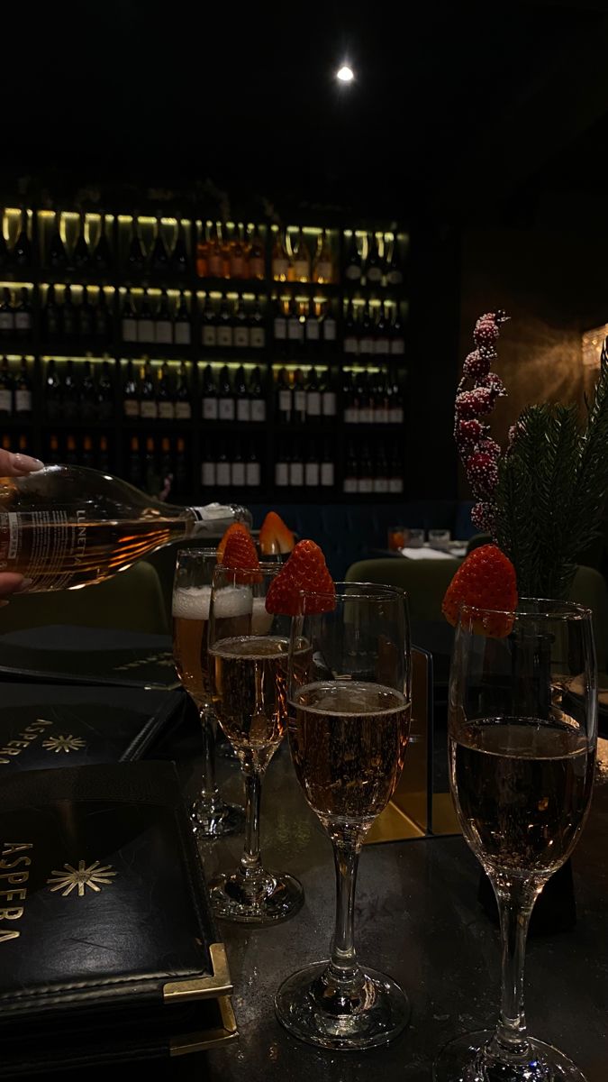 three wine glasses with strawberries sit on a table