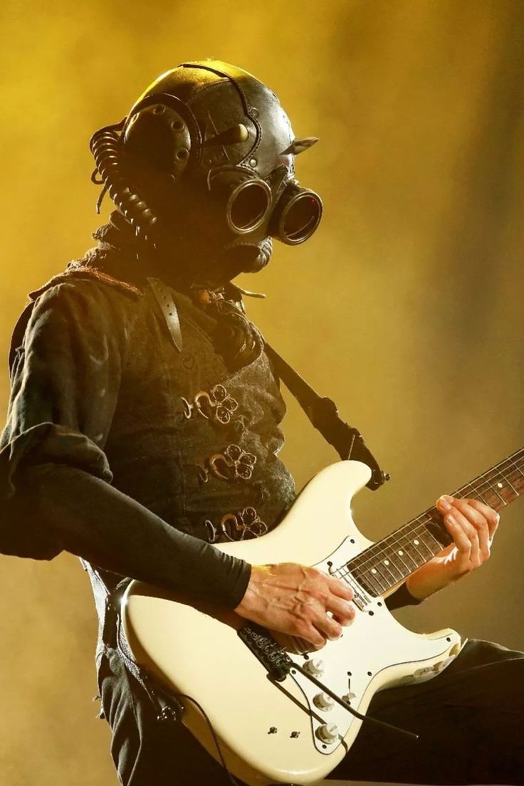 a man in gas mask playing an electric guitar