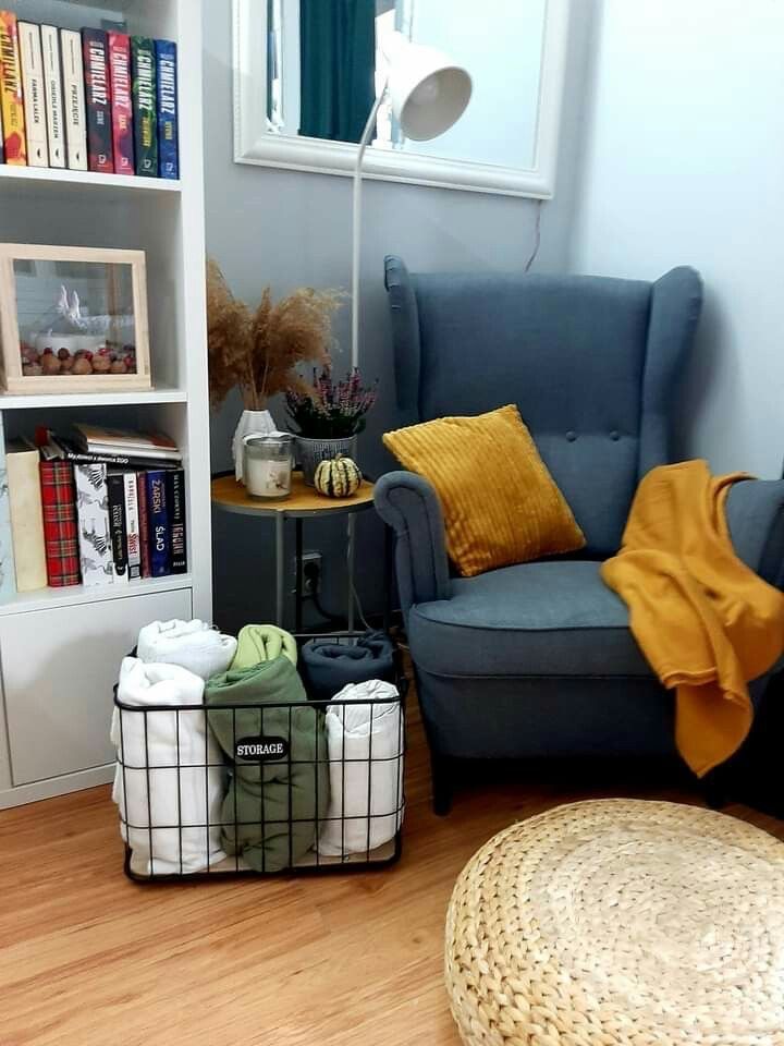 a living room with a chair, bookshelf and two baskets on the floor