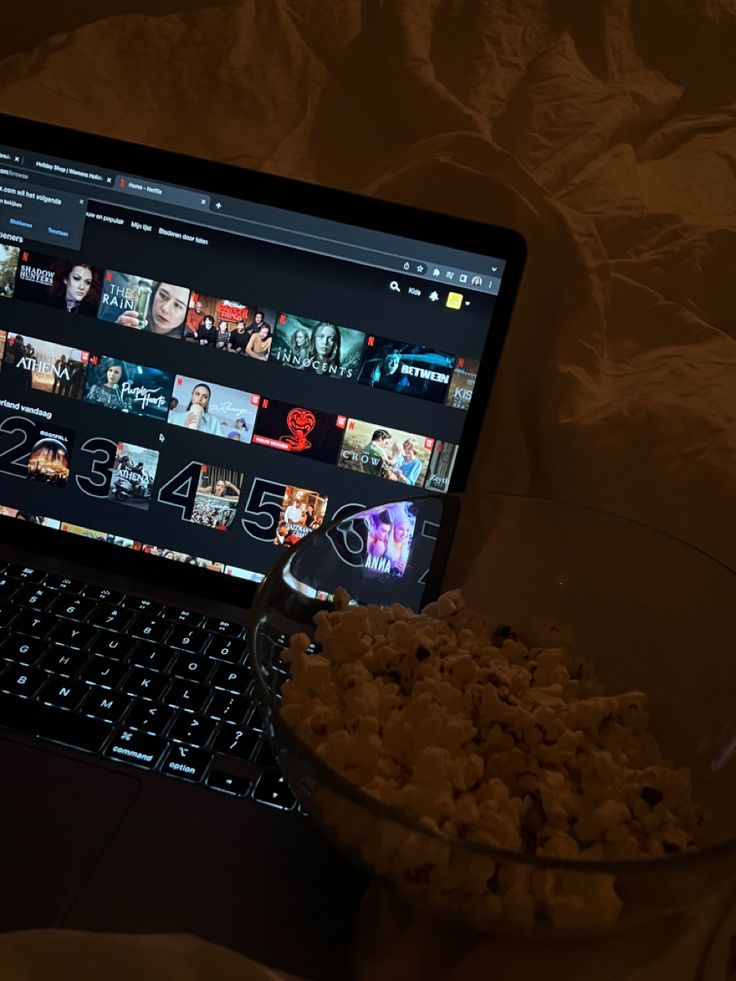 a bowl of popcorn sitting next to a laptop computer