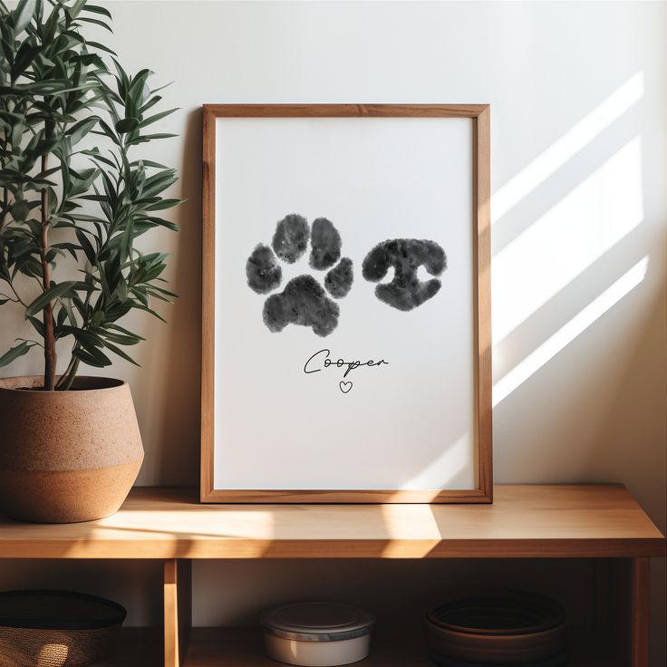 an animal paw print is displayed on a shelf next to a potted plant