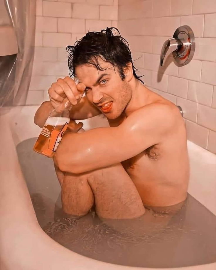 a man sitting in a bathtub holding a beer