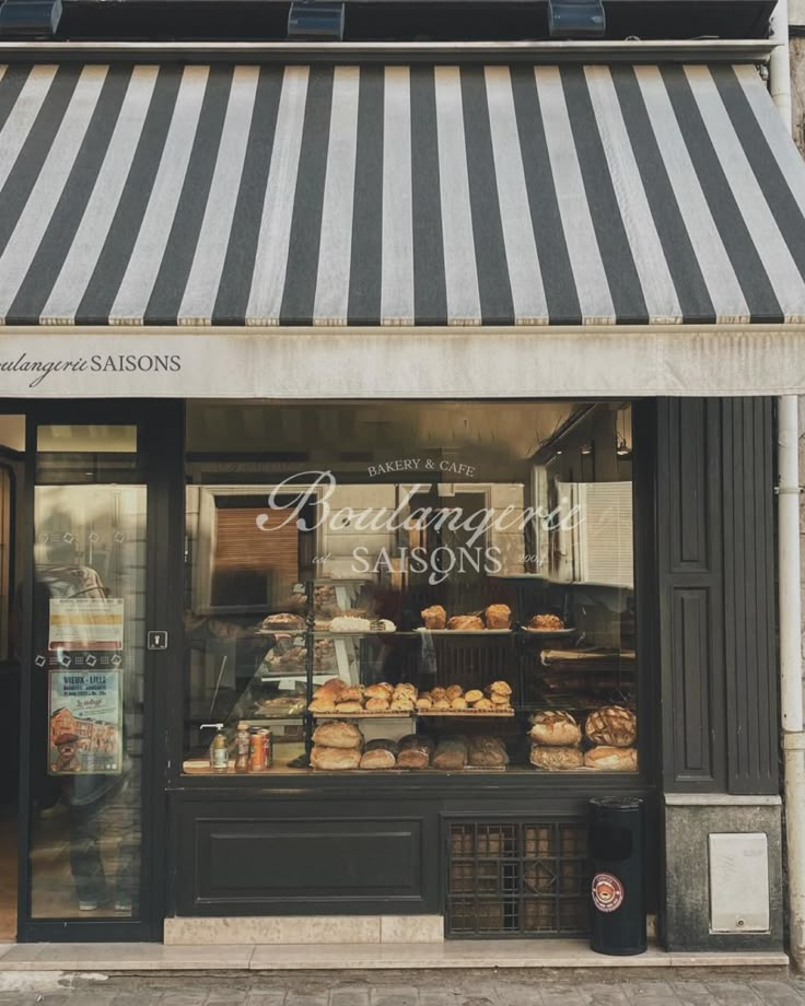 a bakery shop front with striped awnings and pastries on display in the window