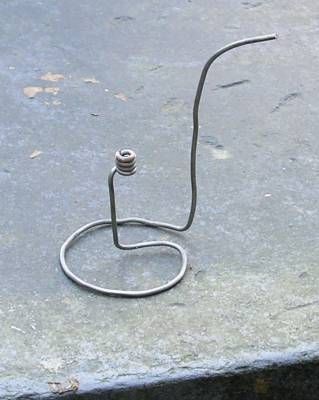 a piece of metal sitting on top of a cement floor next to a wire hook