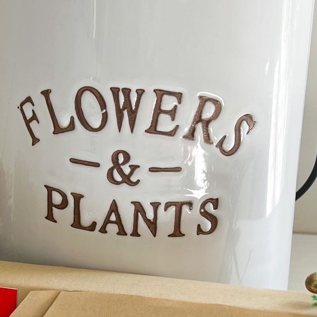 the letters flowers and plants are etched on a large white mug with brown lettering that reads,