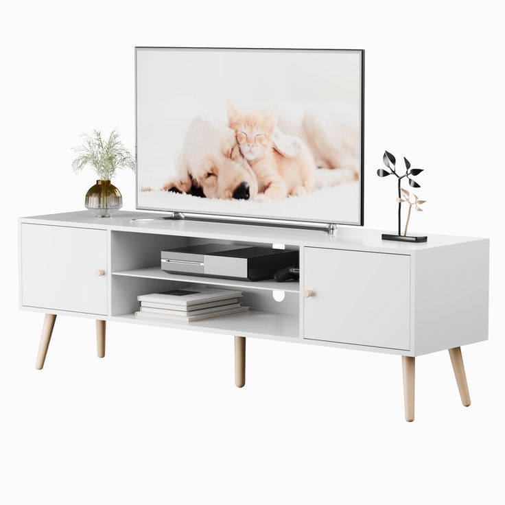 a white entertainment center with a cat on it's side and a potted plant next to it