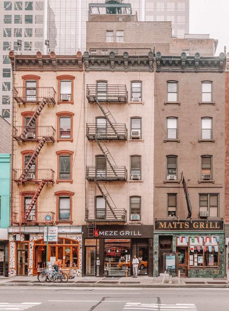 an intersection in front of several buildings with fire escapes on the second floor and third story