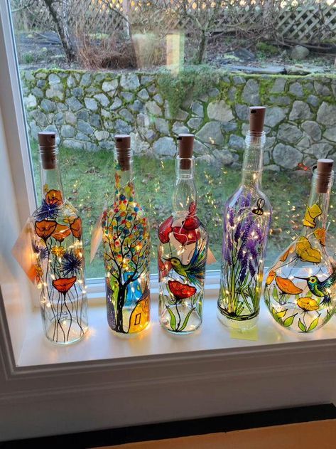 four bottles with different designs on them sitting in front of a window