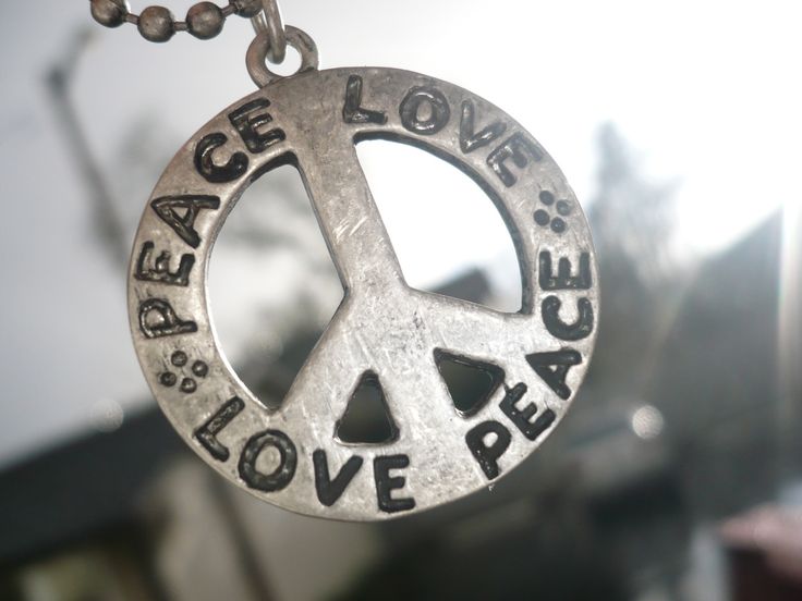 a peace sign is hanging from a chain that says peace, love, and peace