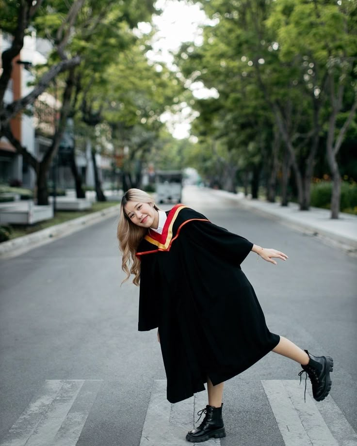 a woman in graduation gown crossing the street with her arms out and legs spread wide