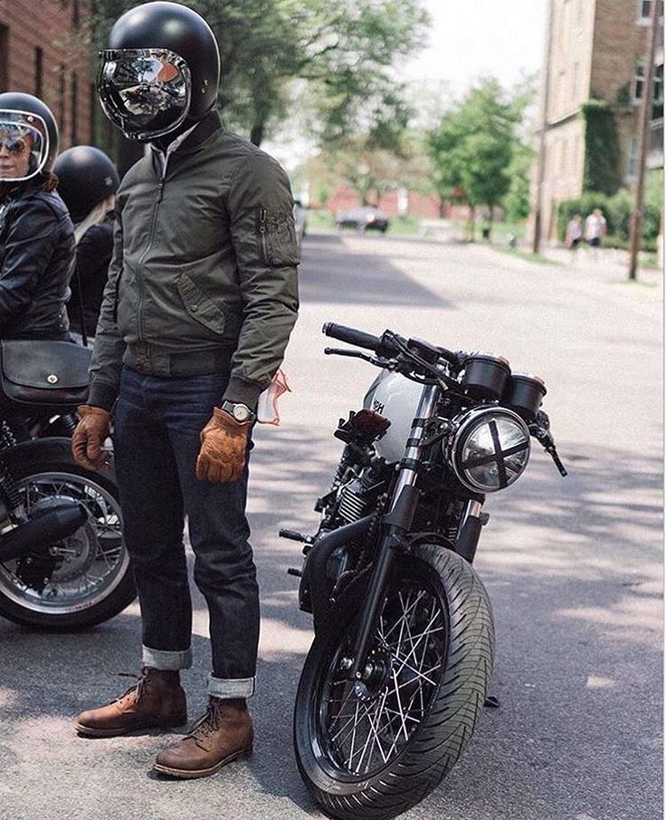 two men standing next to their motorcycles on the street