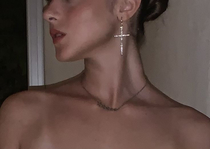 a woman in a white dress wearing cross earrings