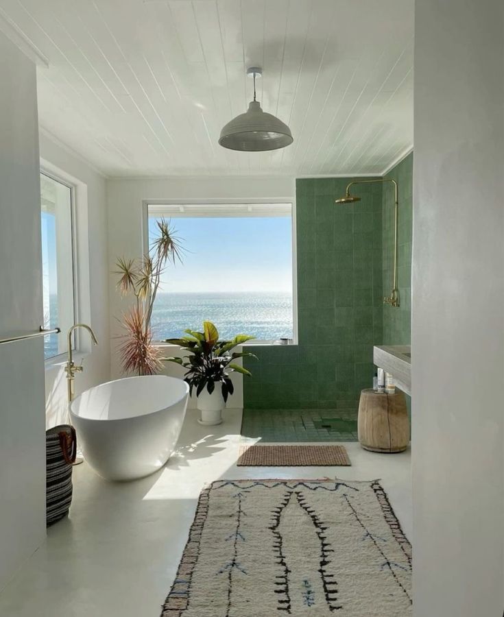 a bath room with a tub a sink and a large window on the side of it