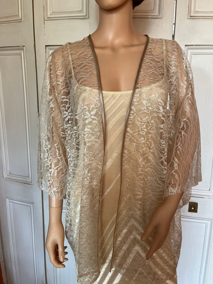 This is a beautiful hand made lace kimono ideal as a cover-up for weddings or special occasions. The lace is champagne floral. It has a satin edging. It can be made in any size from 8 to 24 (UK sizes). It is made in the UK. It is normally sent out to you within 5 days, but I am very happy to make your order a priority if you need it urgently. Just let me know the date needed by. Postage is free in the UK! International postage is £9. I am happy to exchange items or refund your payment if you are Elegant Gold Kimono, Long Lace Kimono With Lace Trim, Party Lace Top In Cream, Party Lace Top With Lace Trim In Beige, Beige Lace Trim Top For Party, Elegant Open Front Summer Shrug, Beige Lace Top For Spring Wedding, Spring Wedding Open Front Kimono, Elegant Cream Lace Top For Party