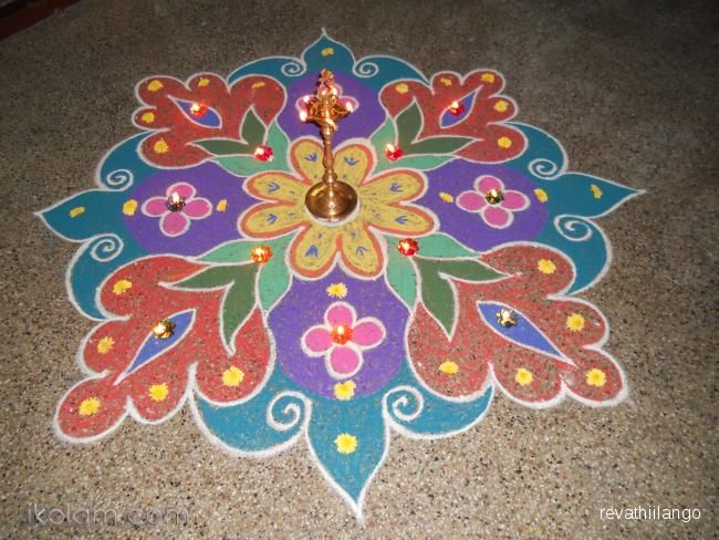 a colorful flower design is on the floor with candles in each one's hands