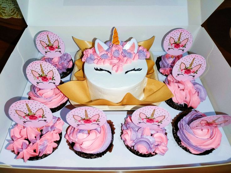 cupcakes with pink and purple frosting in a white box on a table