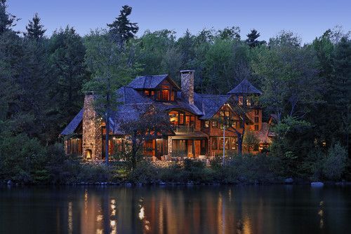 a large house sitting on top of a lake surrounded by trees and water at night