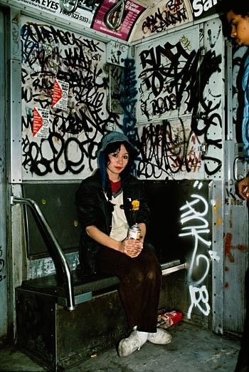 a person sitting on a bench with graffiti all over the walls and floor behind them