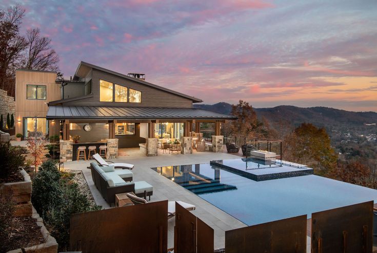 a house with a swimming pool in front of it and mountains in the back ground