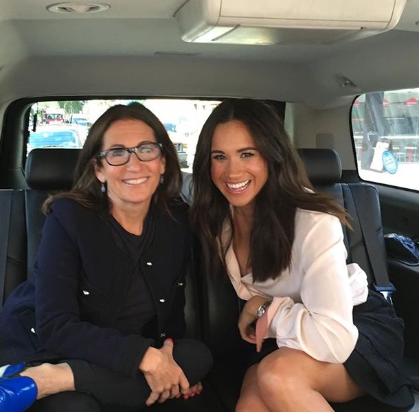 two women sitting in the back seat of a car, one is smiling at the camera