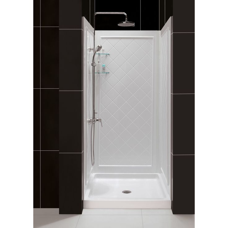 a walk in shower sitting next to a black tiled wall and white tile flooring